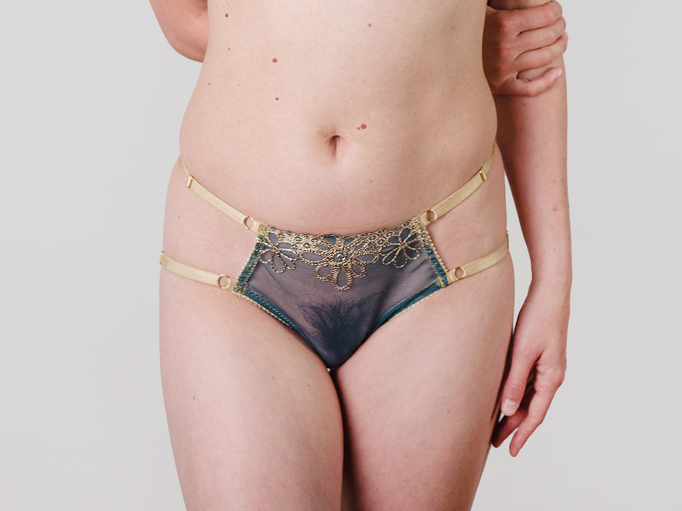 Harness-Panty aus floral bestickter Tüll-Spitze und fein schimmernder Microfaser in den Farben Gold und Petrol
